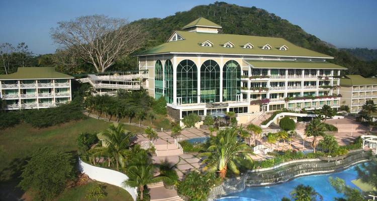 Grand hôtel avec une piscine et un paysage verdoyant qui l'entoure.