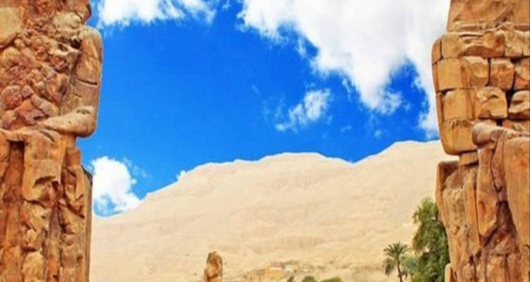 Ancient Egyptian statues and a stunning desert landscape under a bright sky.