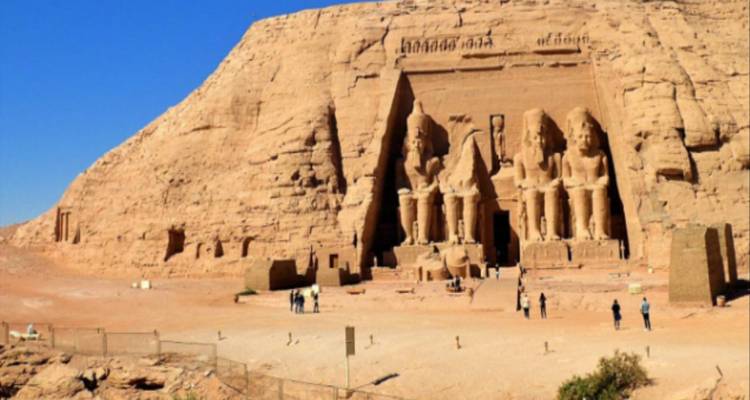 The grand facade of Abu Simbel carved into the rock with small figures for scale.