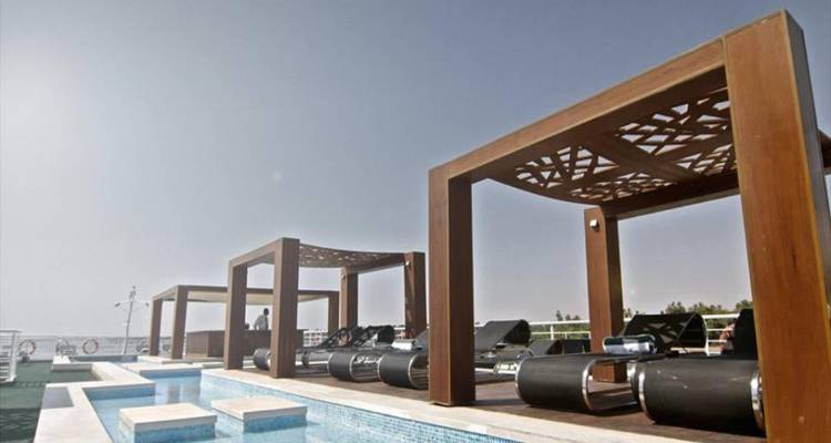 Modern hotel rooftop with lounge chairs and cabanas under a clear sky.