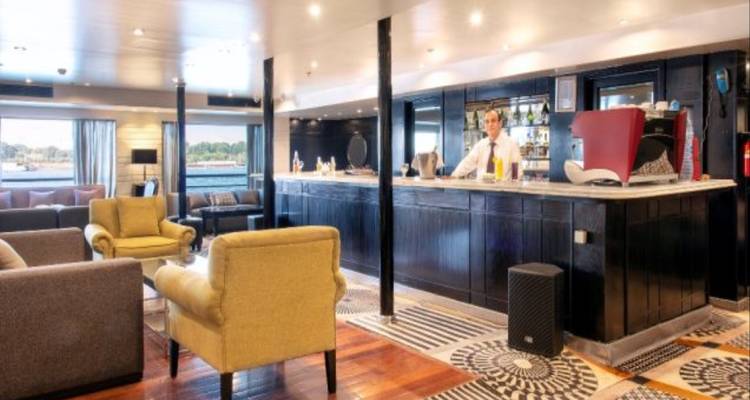 Interior of a cruise ship lounge featuring a bar and comfortable seating.