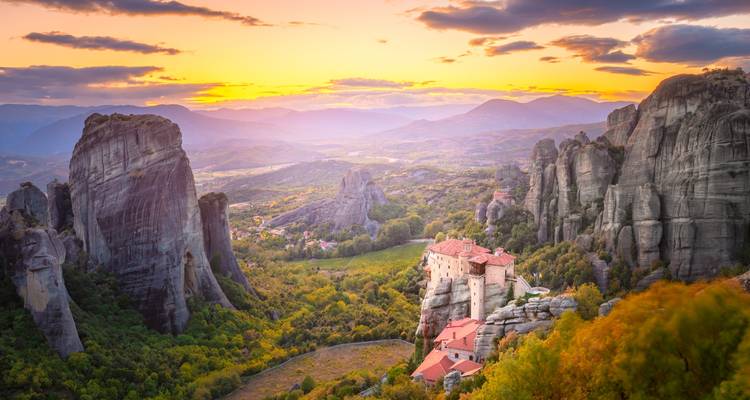 Coucher de soleil spectaculaire sur les monastères de Météores perchés au sommet de piliers rocheux imposants.