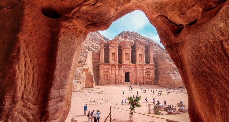 Monastery of Petra framed by a natural stone arch with tourists below
