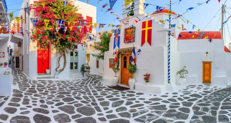 Kleurrijke met vlaggen versierde binnenplaats met witte Cycladeïsche gebouwen op Mykonos.