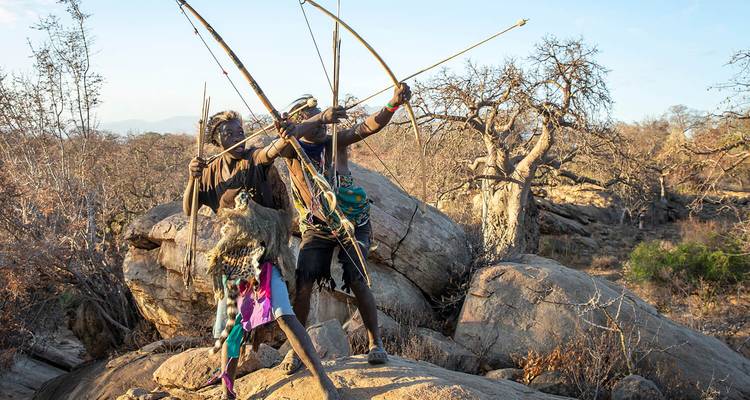 People practicing archery in a rocky landscape.