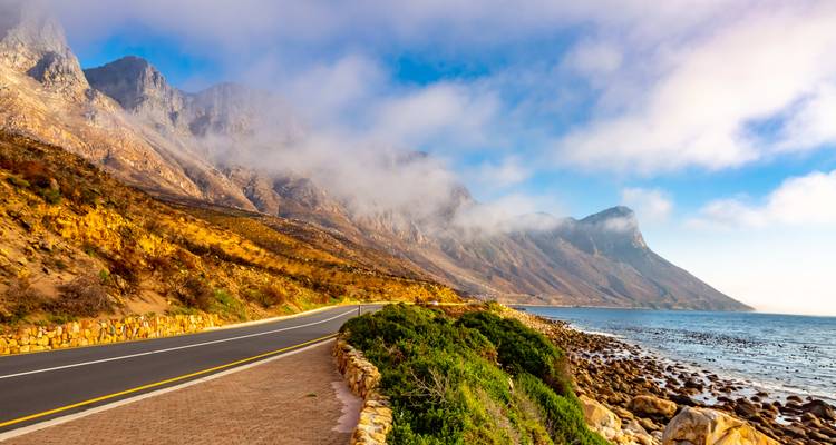 Küstenstraße mit dramatischen Bergen und Meer.