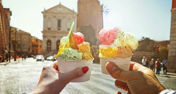 Two gelato cups with a historic building in the background.