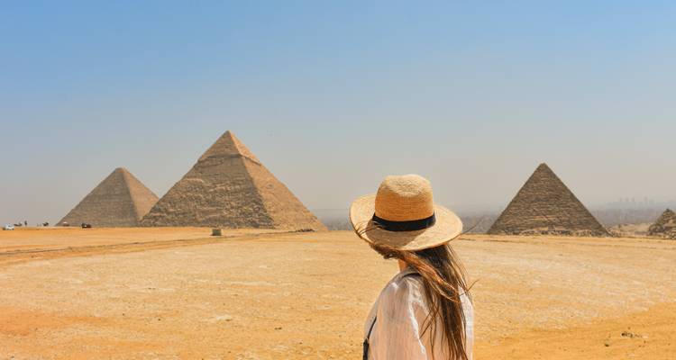 Woman in a hat overlooking the Pyramids of Giza.