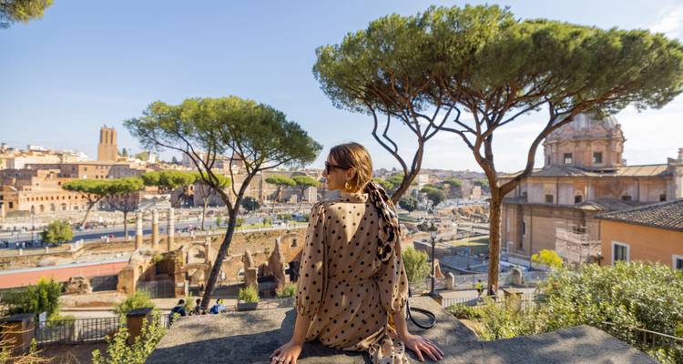 Woman sitting on a viewpoint with Rome skyline behind her.