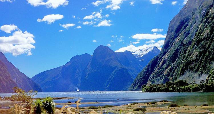 Bright blue sky over dramatic peaks and deep waters of Milford Sound fjord.