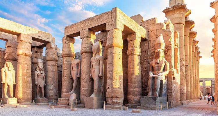Luxor Temple with statues and tall columns under a dramatic sky.