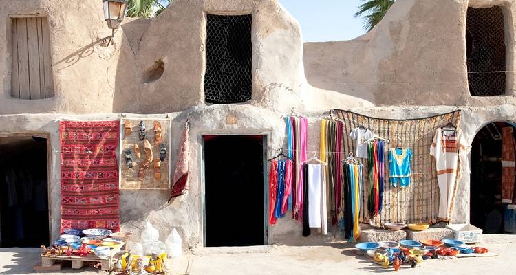 Traditionele Marokkaanse markt met kleding en aardewerk uitgestald.