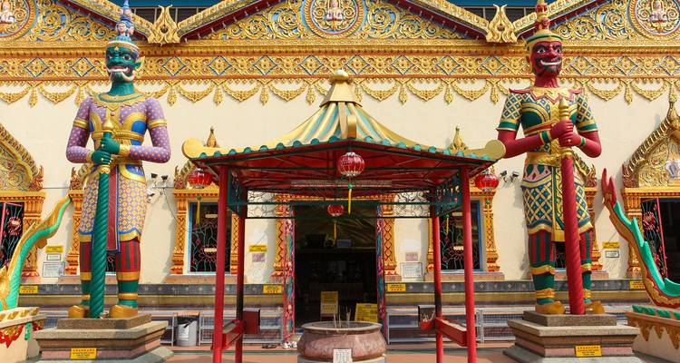 Las coloridas estatuas guardianas flanquean la ornada entrada de un templo budista de estilo tailandés en Penang