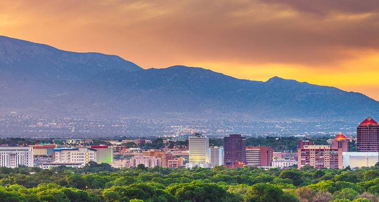 Horizonte de la ciudad con montañas al fondo al atardecer.