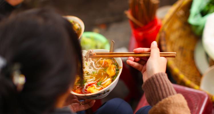 Persona disfrutando de un tazón de sopa tradicional vietnamita de fideos.