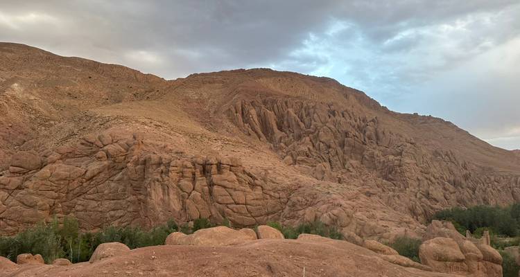 A person sitting on a wall in a rocky desert landscape.