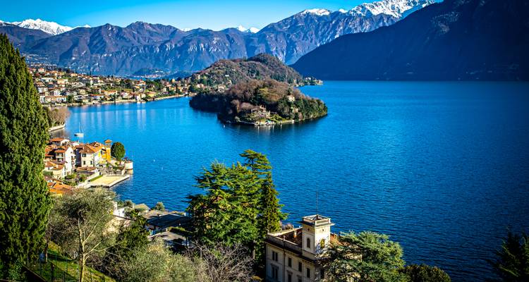 View of a small island in a lake surrounded by mountains.