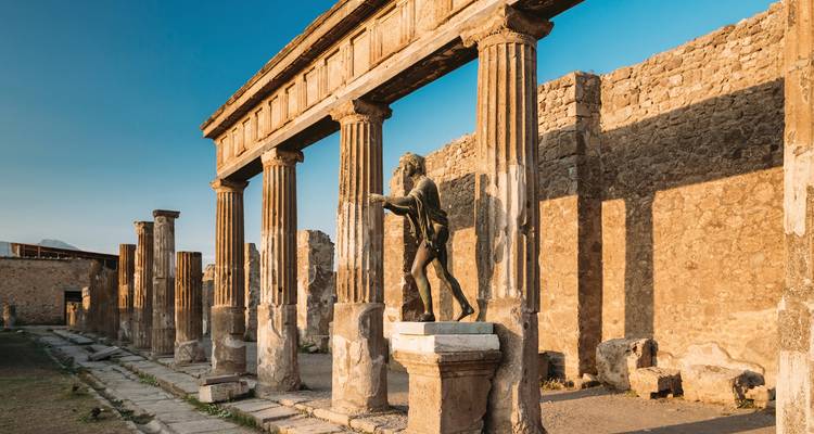 Ancient ruins with statues and columns under blue skies.