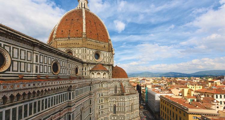 View of a historic city with a large dome and hills.