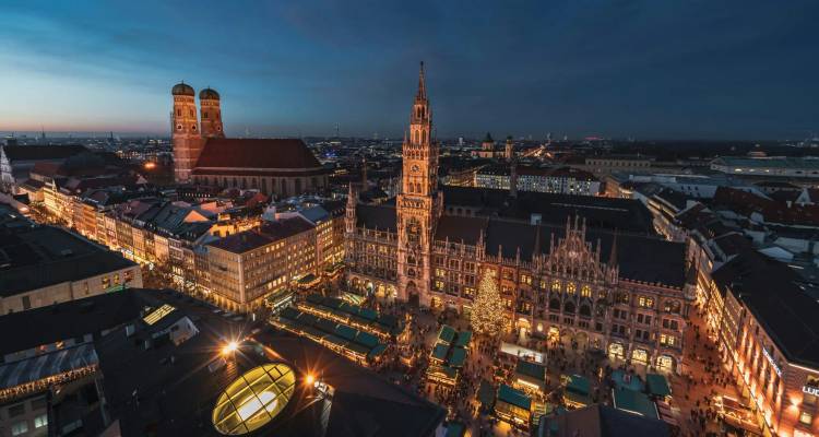 Nachtelijk luchtfoto van Münchens Marienplatz met verlichte kerstmarkt en Frauenkirche.