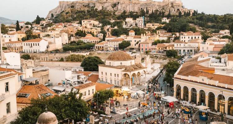 La bulliciosa Plaza Monastiraki llena de gente bajo la colina de la Acrópolis en la hora dorada.