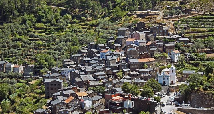 An aerial view of a cluster of traditional stone houses in a Portuguese village.