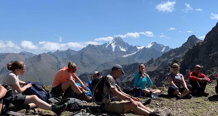 Wandelaars die rusten op een berg met panoramisch uitzicht op bergtoppen en wolken.