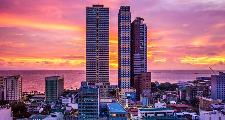 Lebendiger Sonnenuntergangshimmel über Hochhäusern mit Blick auf die Bucht in Manila