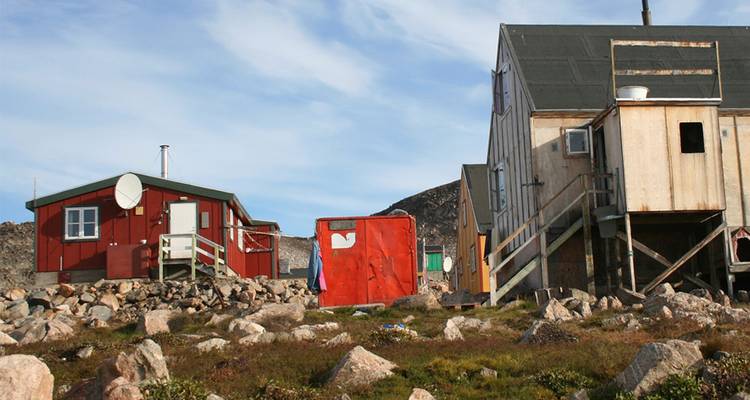 Conjunto de pequeñas cabañas y refugios de investigación ártica dispersos entre la tundra rocosa.