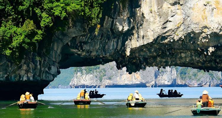 Bateaux naviguant à travers des formations karstiques sur des eaux calmes.
