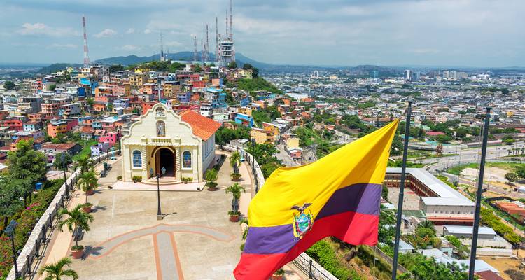 Vue d'une place de ville avec un drapeau et des collines en arrière-plan.