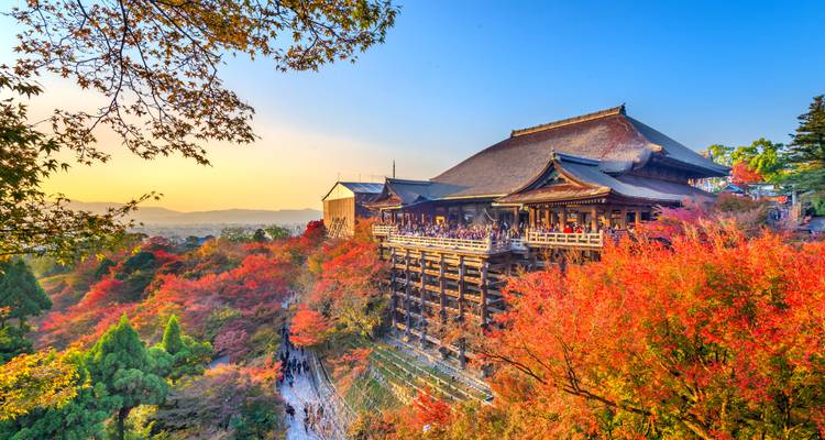 Historic Japanese temple surrounded by colorful autumn foliage.