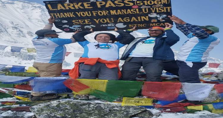 Group holding a sign at a snowy mountain pass