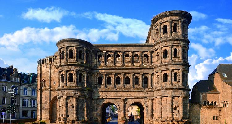 La monumentale porte de ville romaine Porta Nigra se dresse contre un ciel bleu éclatant.