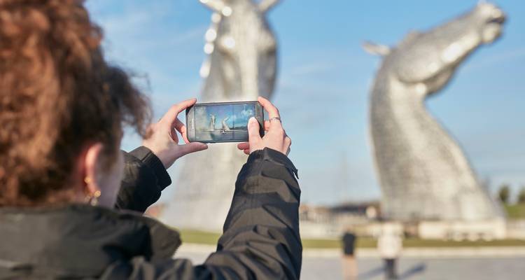 Ein Reisender fotografiert die riesigen Stahlskulpturen von Pferdeköpfen, die als "The Kelpies" in Falkirk, Schottland, bekannt sind.