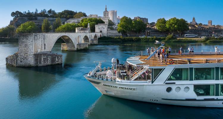 Bateau de croisière fluviale passant sous le pont de pierre historique et la ligne d'horizon de la vieille ville.