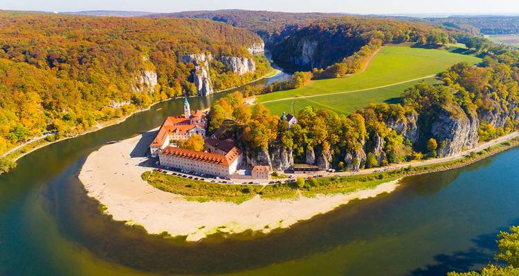 Weitflächige Luftaufnahme des Flusses, der die Weltenburg Abtei inmitten von Herbstwäldern umschlingt.