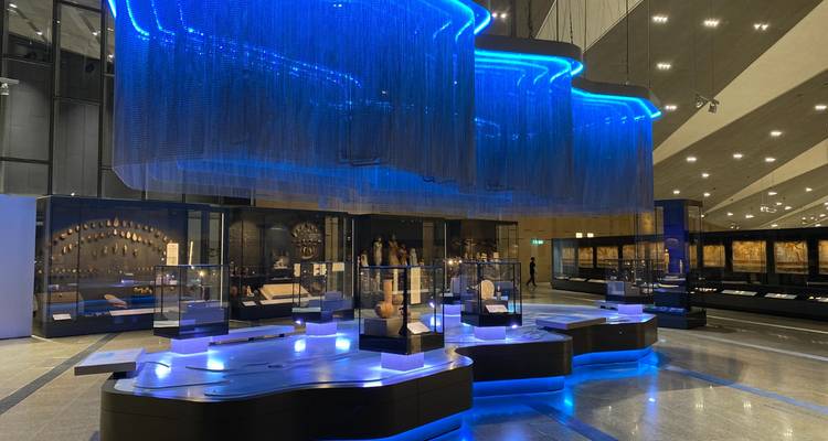 Modern museum interior with blue lighting and display cases.