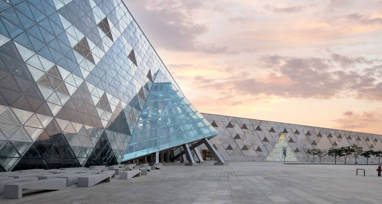 Exterior of a museum with a glass structure and sunset sky.