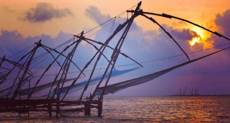 Silhouet van traditionele visnetten tegen een levendige zonsondergang.