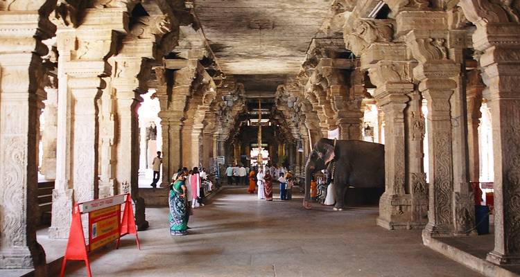 Tempelinterieur met bezoekers en gebeeldhouwde zuilen.