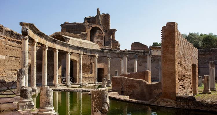 Colonnades en ruine et bassin de réflexion de la Villa d'Hadrien entourés d'anciens murs de brique.