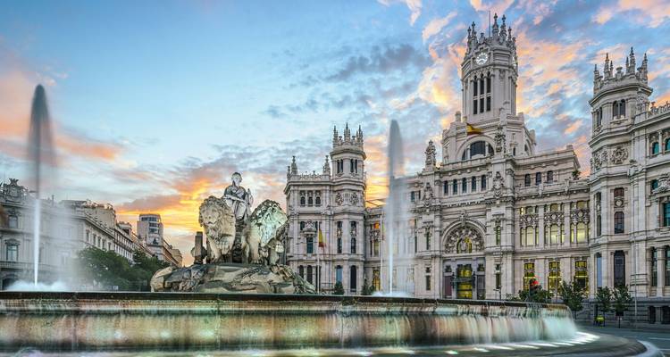 Cibeles-Brunnen und das stattliche Palacio de Cibeles in Madrid, das in der Dämmerung erleuchtet ist, mit sprühenden Fontänen
