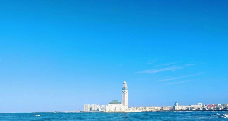 Kustlijn met een eenzame moskee-minaret die boven de stad uittorent, gezien vanaf open water.