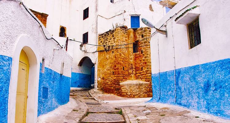Smal steegje van witgekalkte huizen met felblauwe onderwanden in een historische medina.