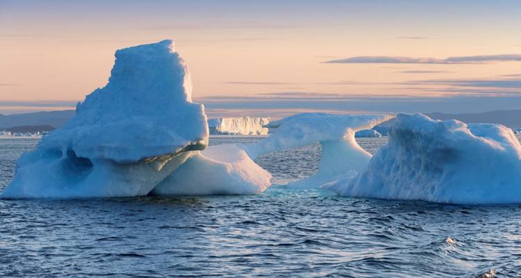 Icebergs floating in the Arctic waters at sunset.