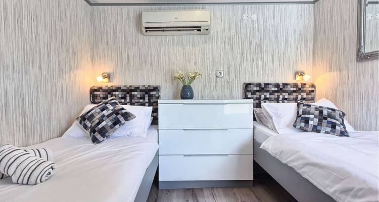 Interior de una cabina de yate con camas gemelas y almohadas decorativas.