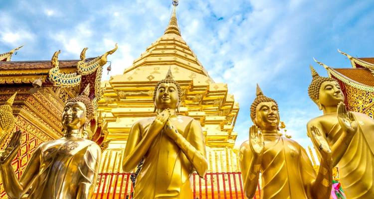 Golden Buddha statues at a Thai temple with blue sky.