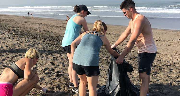 Los voluntarios recogen basura de plástico durante una limpieza comunitaria de la playa en una orilla arenosa muy amplia