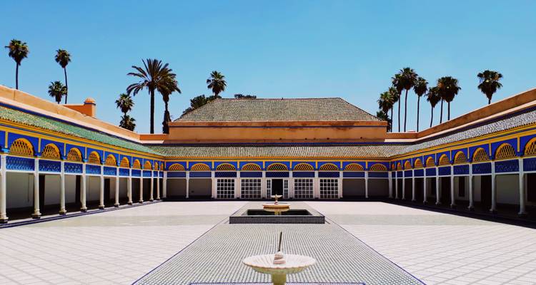 Symmetrical courtyard of Bahia Palace with colorful arches, tiled floor and central fountain under a clear blue sky